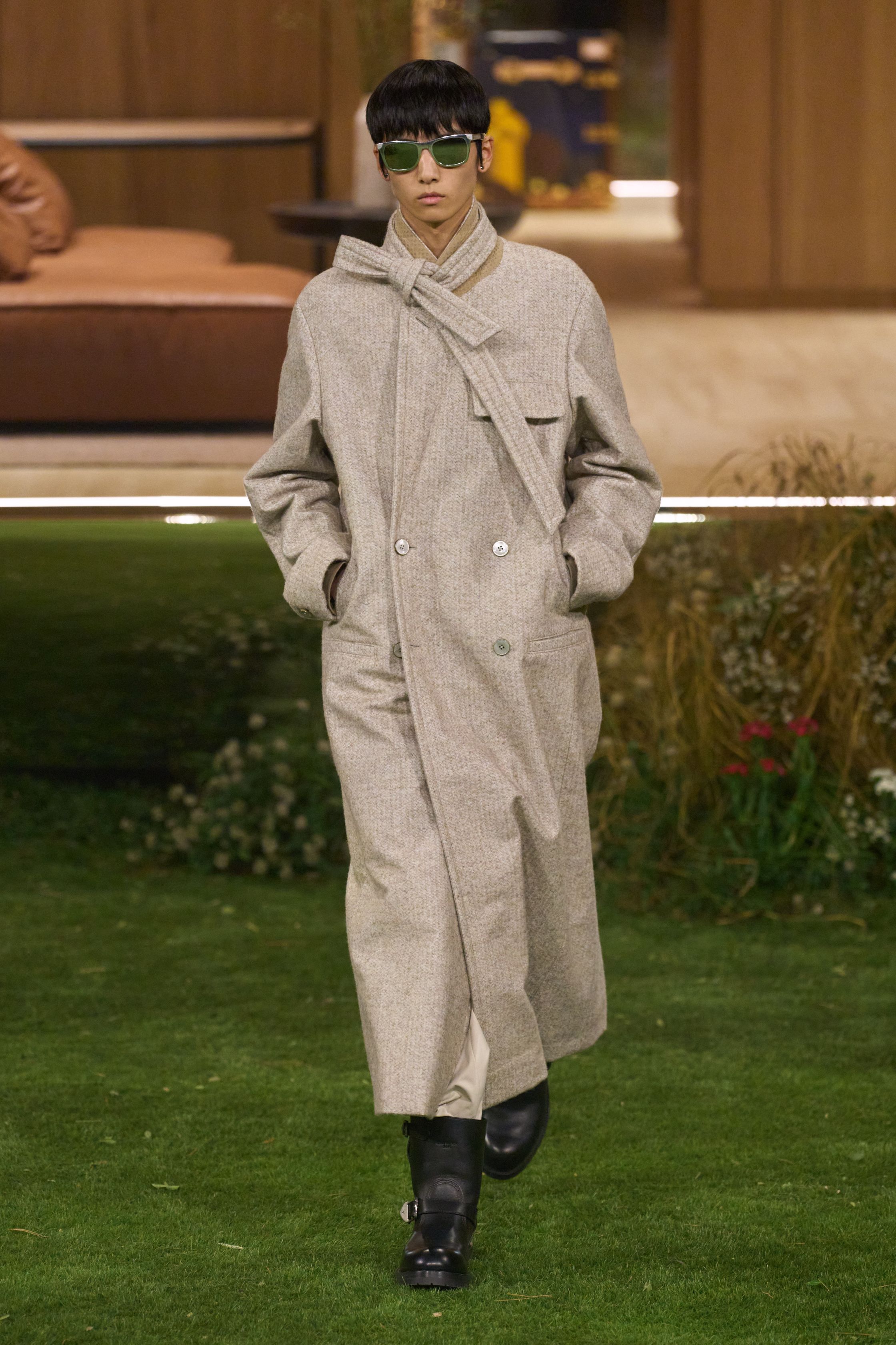Louis Vuitton 26FW 男装以“当代绅士的旅行状态”为核心，在花园式场景中展开一场关于移动、身份与功能的叙事。功能夹克、细致西装、学院感针织与标志性包袋并行出现，色彩回归卡其、橄榄绿、灰褐与深红，呈现出低调却高度可穿的奢华现实主义。系列强化了“穿着中的生活感”，将品牌传统的旅行基因转译为更克制、更日常的现代衣橱方案-顽石频道趋势研究